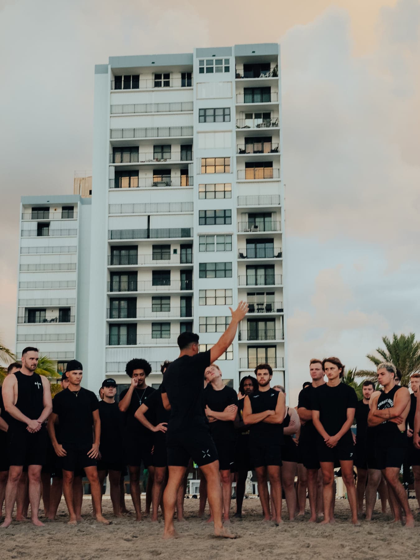 The facilitator addressing a team lined up on the beach in front of a high-rise