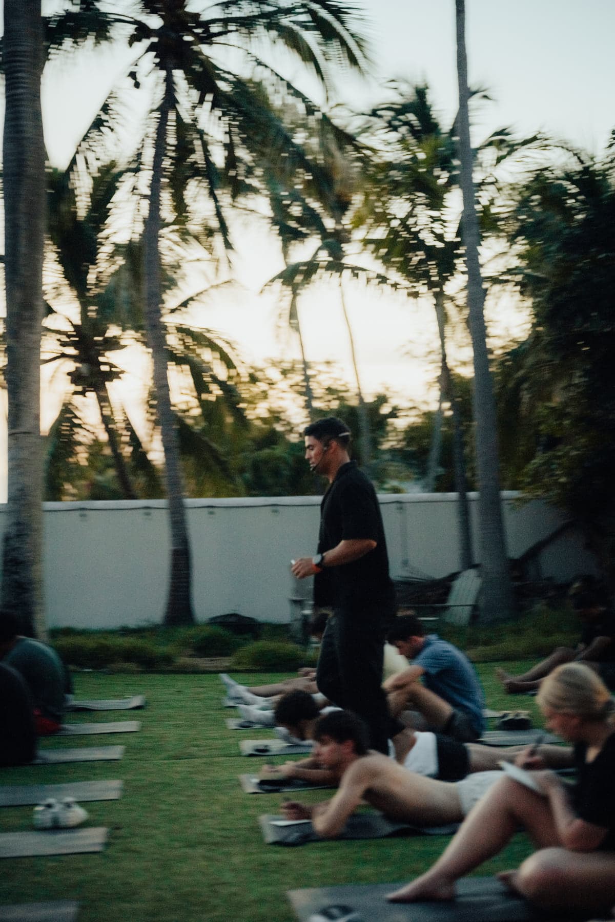 The facilitator walking between rows of participants on mats during an outdoor team session