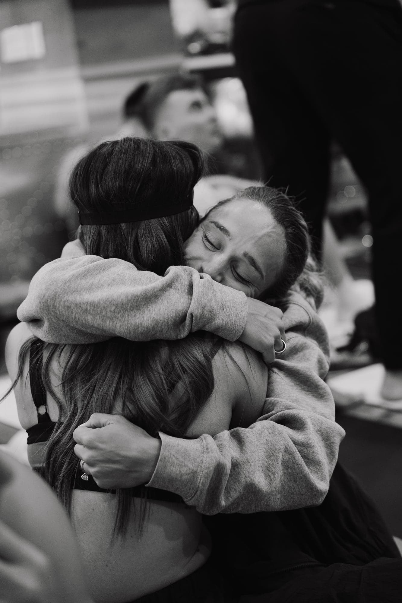 Black-and-white photograph of two participants holding each other in an embrace