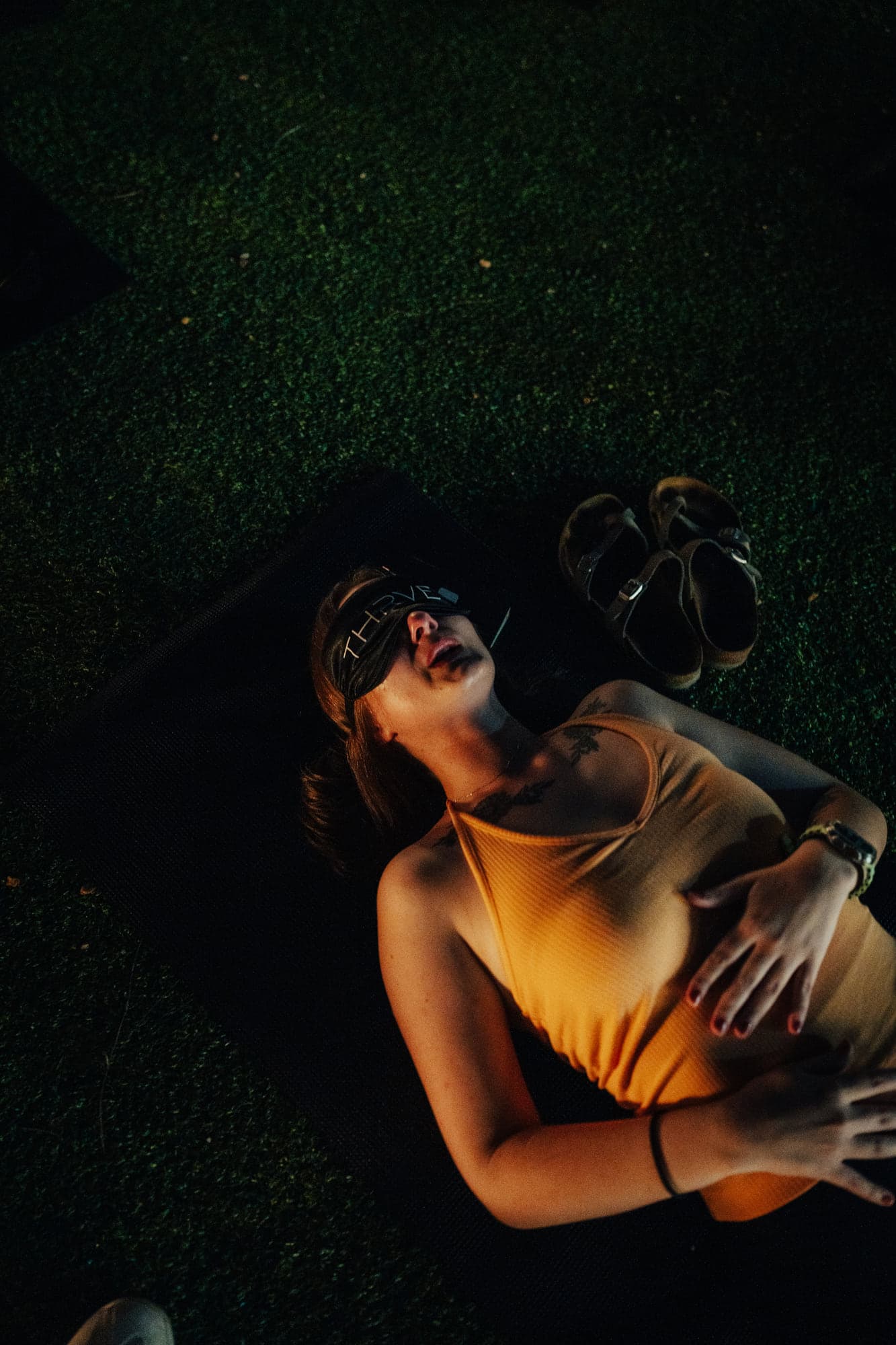 A participant lying on the grass at night with eyes closed, moved during breathwork