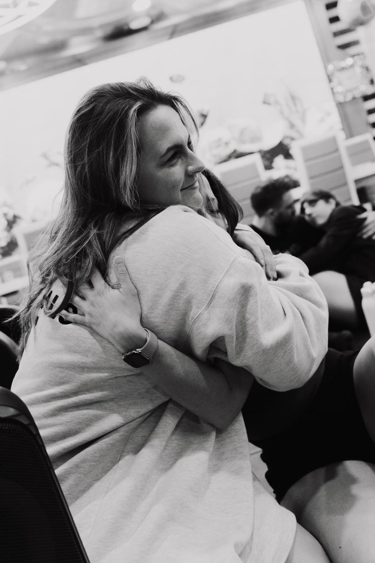Black-and-white photograph of a participant smiling through an embrace